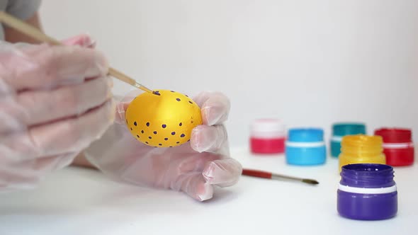 Happy Easter Close Up. A white man painting a yellow Easter egg in polka dot with purple color