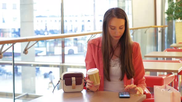 Coffee Break - An Attractive Business Woman Drinking a Coffee To Go and Making a Call on Smartphone