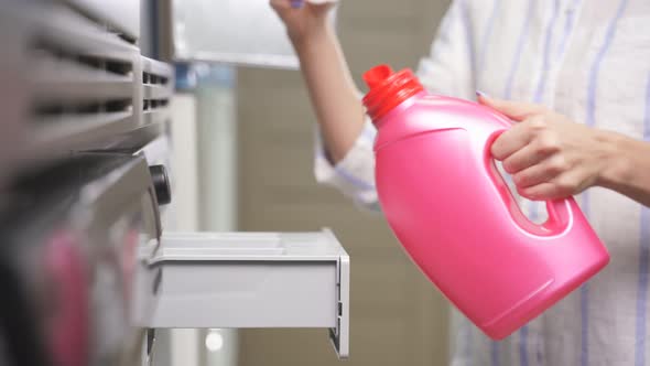 Closeup of a Woman's Hand Pouring Washing Powder Into a Washing Machine in a Public Laundry alt