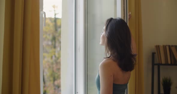 Side View of Elegant Woman Opening Window To Breath Fresh Air Slow Motion. Sensual Girl in Sport Bra