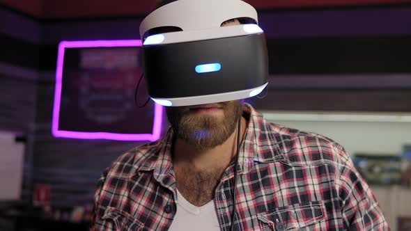 Portrait of a Young Bearded Man Wearing Virtual Reality Glasses in a Game Room alt