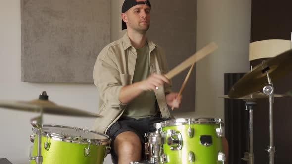 Young Man Practices Playing Drums in Music Studio alt