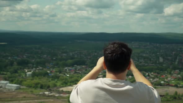 A Young Adult Male Takes a Smartphone Picture From the Top of a Large Hill alt