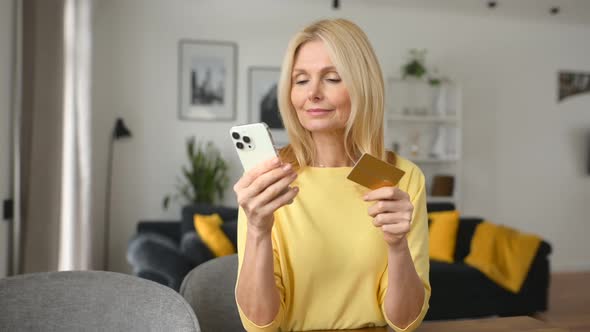 Satisfied Smiling Mature Woman Sitting on the Couch Paying in the Internet Making Order alt