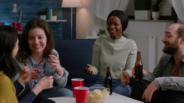 Multicultural Friends Laughing While Sharing Lifestyle Advice Sitting on Couch alt