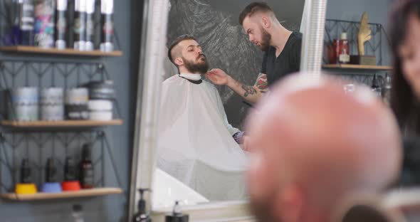 Focus on Mirror on the Grey Wall In Reflection Male Barber Comb in Hands Stays in Front of the Young alt