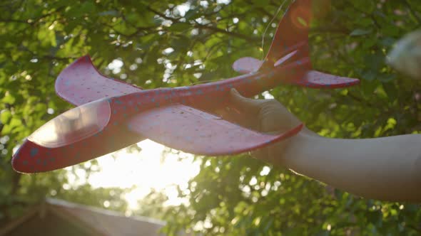 Closeup a Woman's Hand Holding a Toy Plane and Playing It Against the Background of the Sun an Image alt
