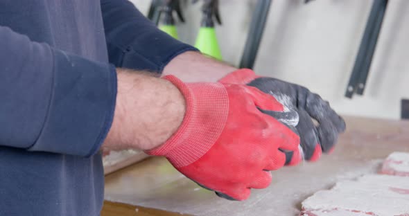 Man in Rubber Gloves Shakes Off Plaster Residue From Hands alt