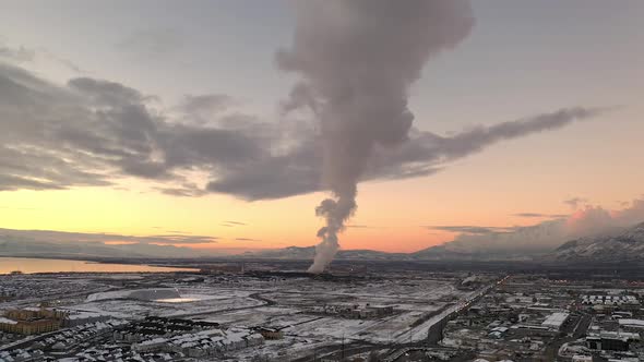 Aerial winter sunset view flying backwards viewing smoke from factory alt
