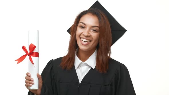 African American Young Graduate Female in Black Academic Dress Holding Her Diploma and Showing Ok alt