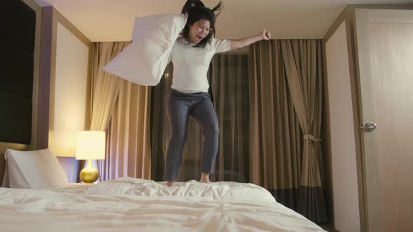 asian female woman jumping on bed resting after successful travel journey