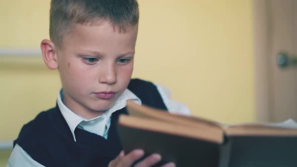 Upset Boy Turns Pages of Textbook Preparing for Test at Home alt