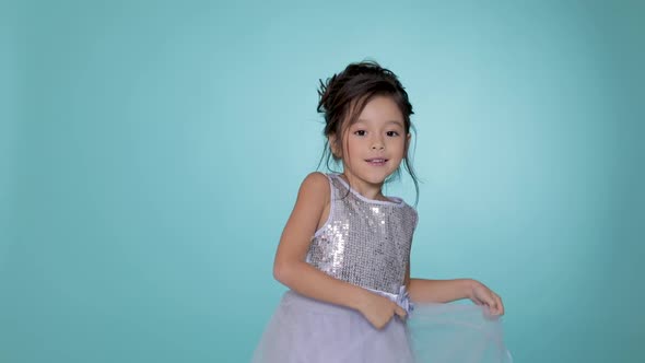 Beautiful Little Child Girl in Silver Dress Dancing on Blue Background