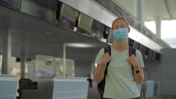 Woman in Mask at Empty Airport at Check in in Coronavirus Quarantine Isolation Returning Home Flight alt