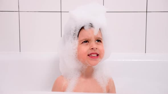 Three Year Old Child with Big Brown Eyes Is Sitting in a White Bathroom alt