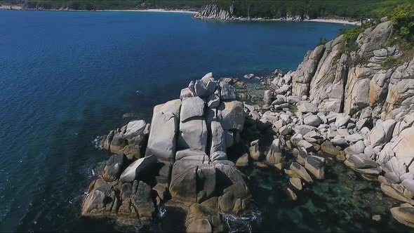Aerial Shot Moving Along the Coastline of Deep Blue Sea Along a Dramatic Cliff Edge on Sunny Day alt