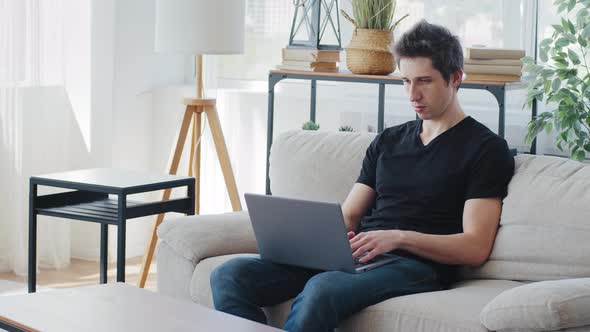 Concentrated Adult Business Man Millennial Guy Student Male Freelancer Client Buyer Sitting on Couch alt