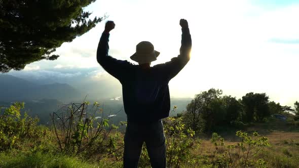 Reaching The Top. Man Raise Up Hands on Beautiful Mountain Lanscape on Sunrise. Feelling Happy