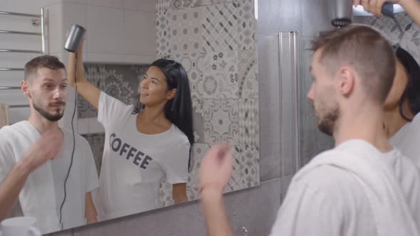 Young Joyous Woman Blow Drying Hair of Husband alt