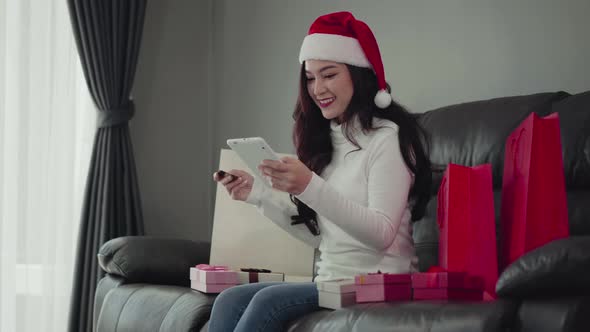 woman in santa hat shopping online for Christmas gift with digital tablet in the living room