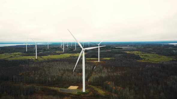 Amazing Aerial Panoramic View of Windmill Turbine Farm Generating Power in Autumn Forest Lake Field alt