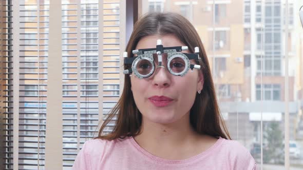 Young Smiling Woman Sitting in the Optometry Device for Vision Test alt