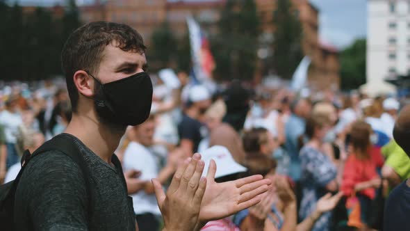 Clapping Protester Man in Face Mask in Political Rally Crowd on City Streets alt