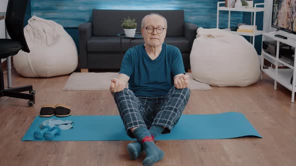 Aged Man Doing Meditation While Sitting in Lotus Position alt