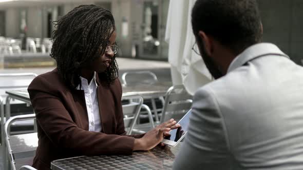 Serious Business Partners Talking at Outdoor Cafe. alt