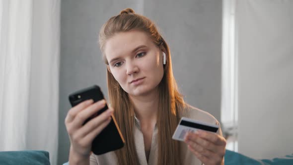 Smiling Young Woman Customer Holding Credit Card and Smartphone.