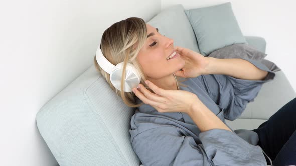 Portrait of cheerful european woman in headphones listening to music