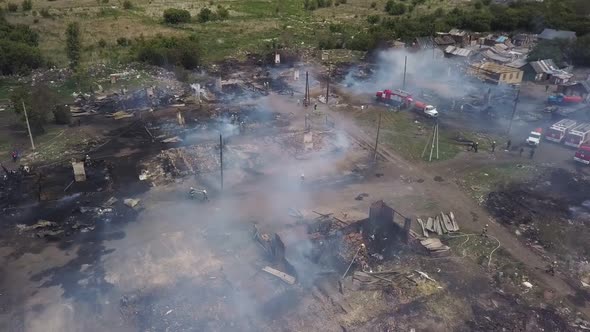 Working Firefighters on Smouldering Ruins in Village, Aerial View