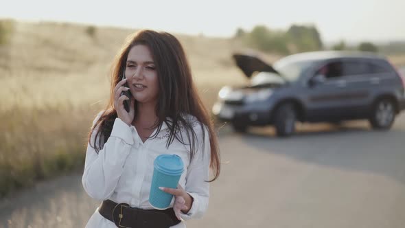 Alone Lady Holds a Cup of Tea and Emotionally Talks on Phone at Broken Car alt