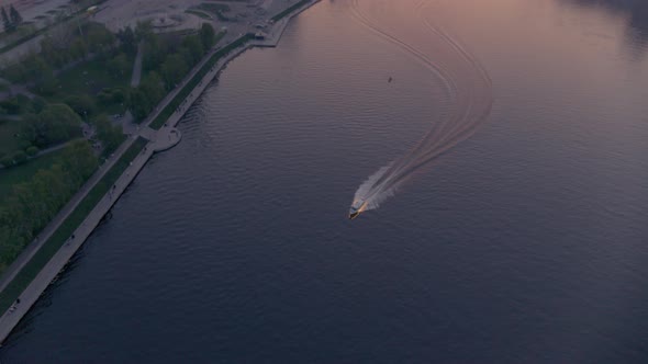 An Aerial View of a Boat That Floats on a River in the City Centre at Sunset alt