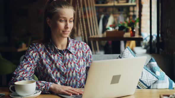 Cheerful Young Lady Communicating with Laptop Skyping Talking Smiling in Cafe alt
