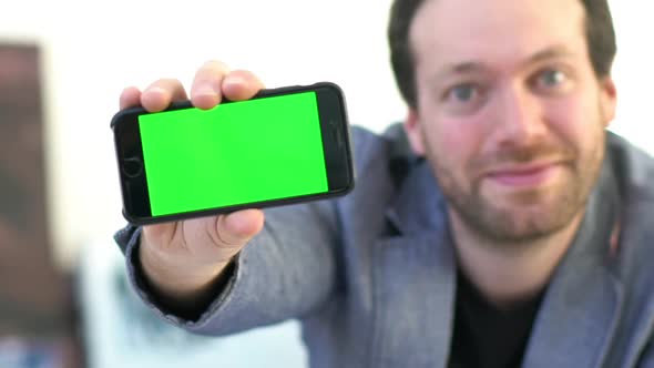 Businessman showing smartphone screen to camera