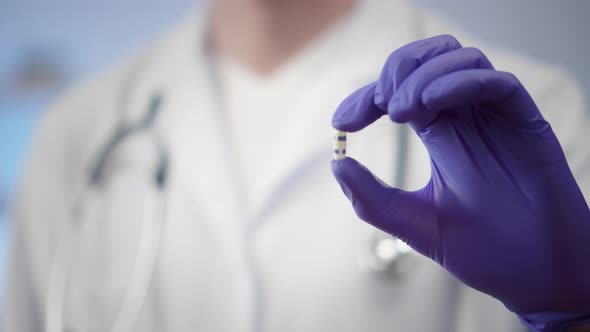 Cropped Shot of Doctor on Latex Gloves Holding Capsule alt