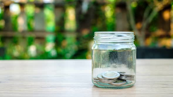 Saving money concept.Money on glass jar with bokeh background. Stop motion	