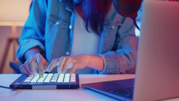 asia girl dj use launchpad synthesizer keyboard sound mixer wear headphone made music in laptop. alt