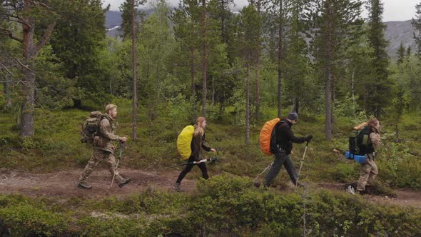Group of Tourists with Large Backpacks Goes the Forest Path