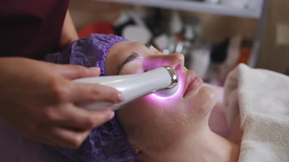Beautician with Microdermabrasion Device Doing Face Exfoliation To Young Woman Lying at Spa alt