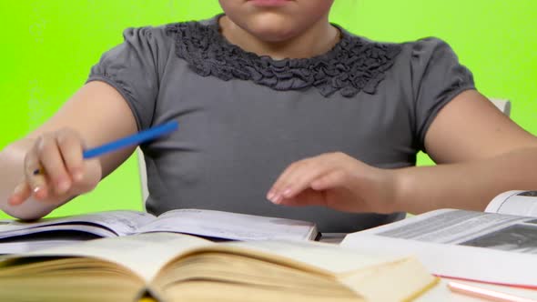 Girl Leafing Through a Book and Writing in a Notebook. Green Screen. Close Up alt