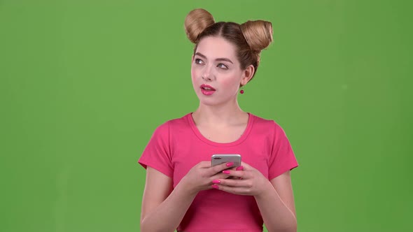 Teen in a Pink Topic Prints a Message on the Phone. Green Screen. Slow Motion alt