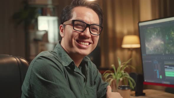 Asian Male Video Editor Works With Footage And Sound On His Personal Computer alt