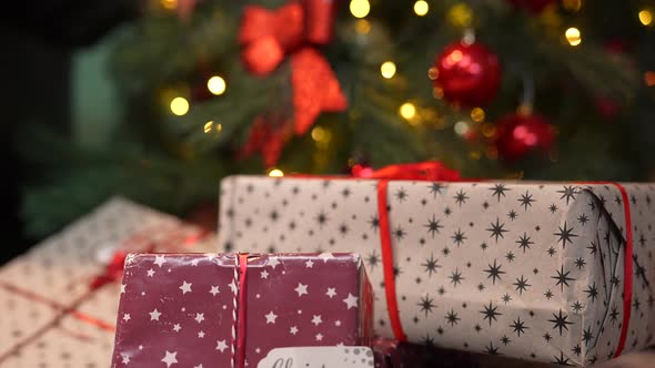 Beautiful Gift Boxes Lie Near the Christmas Tree Decorated with a Glowing Garland and Balls alt