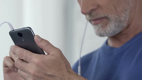 Man Composing Playlist of His Favorite Songs on Smartphone, Accessible App alt