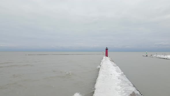 View out Lake Michigan on a gray cloudy day in winter. Waves crashing against pier making ice.