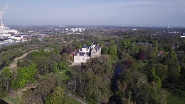 Rotating around Schloss Wolfsburg Castle and forest, Aerial shot, Germany alt