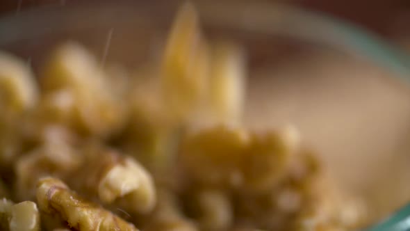 Slow motion footage of walnut pieces falling into a dish alt