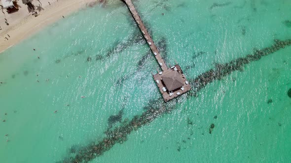Beautiful aerial view of dock above the peaceful greenish sea on sunny day.